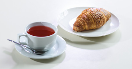 Fruit tea and delicious fresh croissant on the table in a cozy coffee shop