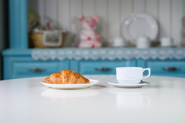 Fruit tea and delicious fresh croissant on the table in a cozy coffee shop