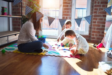Beautiful teacher and toddlers learning maths using numbers game around lots of toys at kindergarten