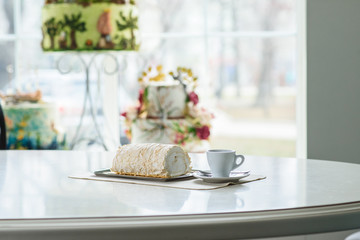 A delicious roll of bezrukov and a cup of coffee on a table in a cozy coffee shop