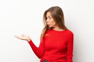 Young blonde woman with red sweater over isolated white background holding copyspace imaginary on the palm