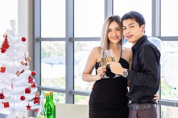 Attractive young couple celebrate Christmas and New Year in party, clinking champagne glass, with snack and beverage on table