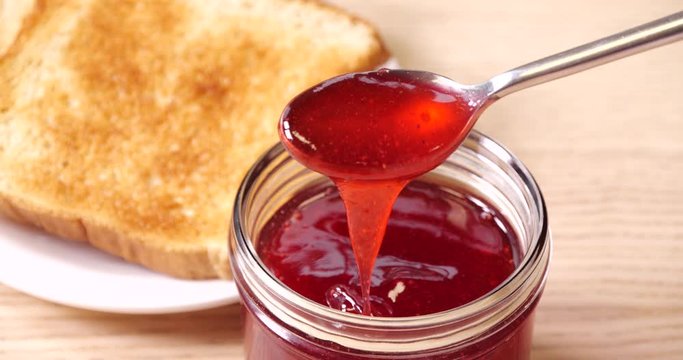 Delicious strawberry jam in glass jar, closeup