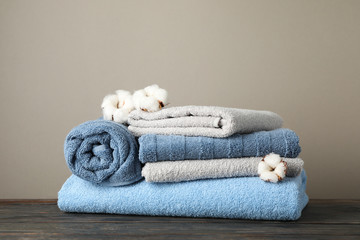 Folded towels and cotton on wooden table against grey background, space for text