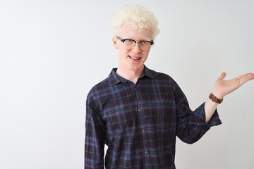 Young albino blond man wearing casual shirt and glasses over isolated white background smiling cheerful presenting and pointing with palm of hand looking at the camera.