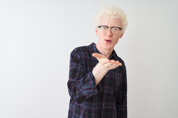 Young albino blond man wearing casual shirt and glasses over isolated white background looking at the camera blowing a kiss with hand on air being lovely and sexy. Love expression.