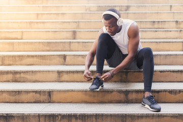 African American man tied up shoes on stairs after running exercised.