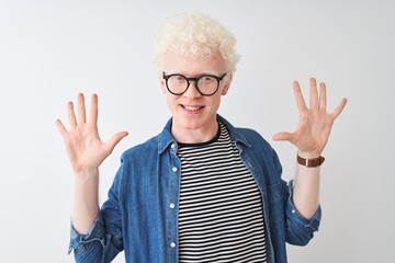 Young albino blond man wearing denim shirt and glasses over isolated white background showing and pointing up with fingers number ten while smiling confident and happy.