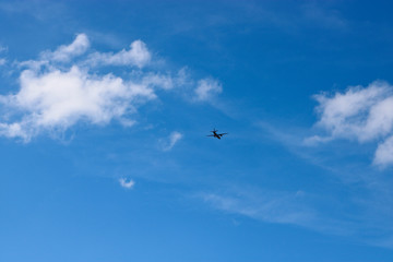 A plane flying against a blue sky with cirrus and cumulus clouds. The concept of travel, vacation, adventure.