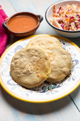 Salvadoran pupusas with coleslaw and tomato sauce on wooden background