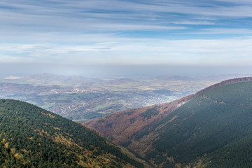 Obraz premium Hills and mountains on the horizon of beautiful nature with city in the forest valley view into vast distance of the Beskids Area during a windy sunny day captured in Radhost Pustevny area
