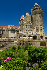Fototapeta na wymiar Garden flower bed and Gothic revival towers of Casa Loma castle in Toronto