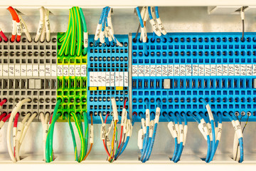 Close up of multicolored wiring connectors or terminal block for industrial electronic with marked cable wires. Number of lead-through terminals to connect the electrical cabinet. Block with wire. - obrazy, fototapety, plakaty