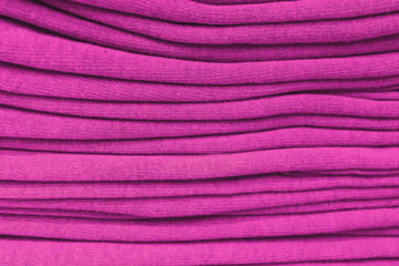 Fototapeta na wymiar clothes stacked close-up, fabric texture, bright colors, neat red pink stacks