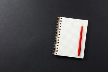 notebook with red pen on black background