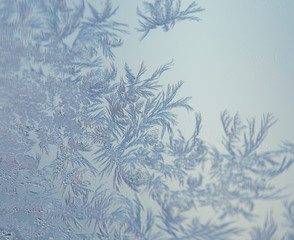 Magical frost ornaments on the window. Closeup of frozen ice on the glass. Macro shot with shallow depth of field.