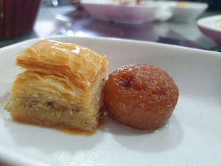 Oriental Sweets Baklava and Sekerpare / Kemalpasa, Turkish Traditional Desserts on a White Plate,  Pastry Made of Layers of Filo Filled and Chopped Nuts, Popular Desserts in the Turkish Cuisine