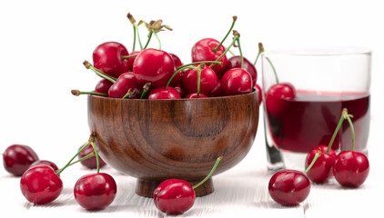 .sweet cherries in a plate and a glass of juice on a white background