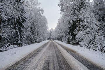 car tracks in the snow on the winter road in sunny day