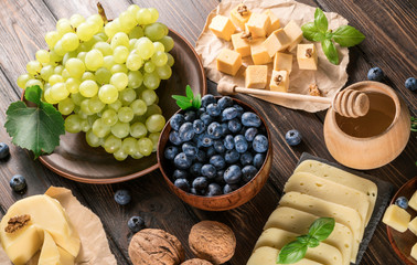 cheese, blueberries and grapes on a wooden background