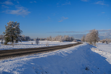 car tracks in the snow on the winter road in sunny day