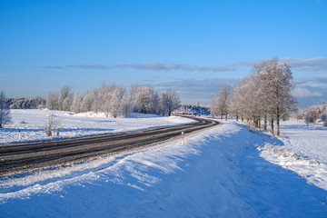 Obraz premium car tracks in the snow on the winter road in sunny day