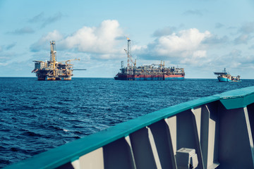 FPSO tanker vessel near Oil Rig platform. Offshore oil and gas industry. Flare is burning with smoke. View from supply vessel