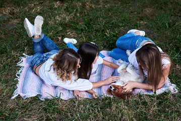 Two young blond women and one brunette girl, wearing white t-shirts, lying on mexican blanket on...