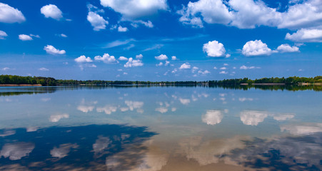 Panoramic background - blue sky with white clouds is reflected in the lake