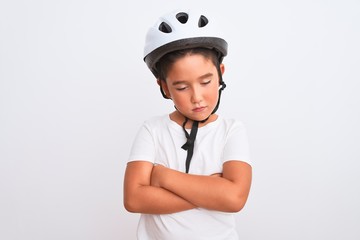 Beautiful kid boy wearing bike security helmet standing over isolated white background skeptic and nervous, disapproving expression on face with crossed arms. Negative person.