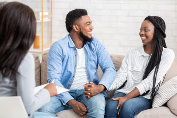 Happy black couple after successful marital therapy with psychologist