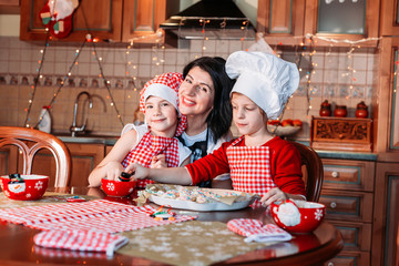 Cute, little girls in chef apron making ginger cookies with their mom.