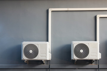 Two compressors of air conditioner placed on the wall outside the building