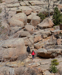 Tourists climbing mountain with boulders