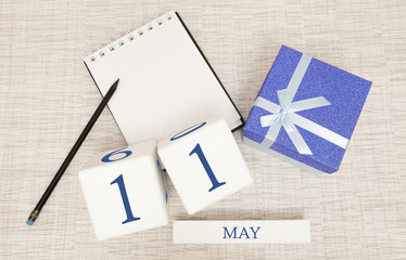 Calendar with trendy blue text and numbers for May 11 and a gift in a box.