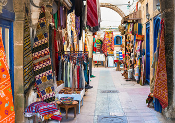 Fototapeta na wymiar Moroccan carpets and clothing for sale on the narrow streets of Essaouira, Morocco