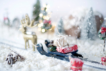 Miniature sled loaded of gifts a on snowy background