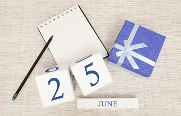 Calendar with trendy blue text and numbers for June 25 and a gift in a box.
