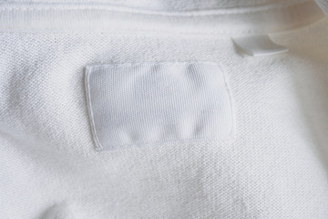 Blank white clothes label on new cotton shirt background