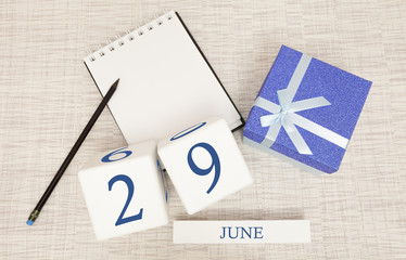 Calendar with trendy blue text and numbers for June 29 and a gift in a box.