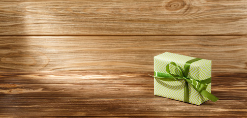 Gift box with ribbon on wooden background