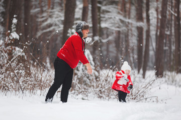 Portrait of happy little girl in red coat with dad having fun with snow in winter forest. girl playing with dad.