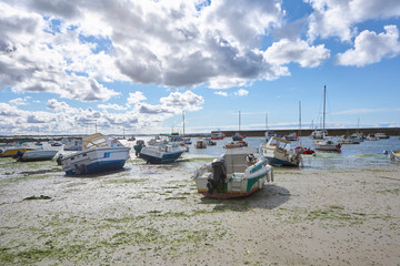 Sunny summer day at the coast, low tide at a small idyllic harbour with nice boats, view to the sea