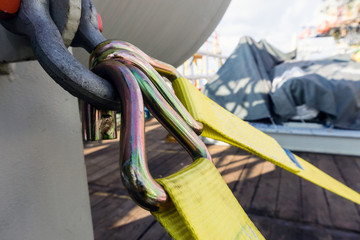 Cargo strap hook secured to ashckle for tie-down of a vessel on deck of a construction work barge...