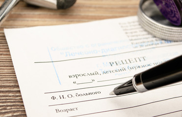 A medical prescription form at the doctor’s workplace with a seal, pen and neurological hammer.