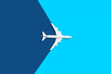 Fotobehang Platliggend ontwerp van reisconcept met vliegtuig op blauwe achtergrond met kopieerruimte © Angelov