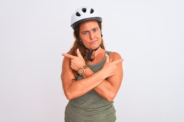 Middle age mature cyclist woman wearing safety helmet over isolated background Pointing to both sides with fingers, different direction disagree