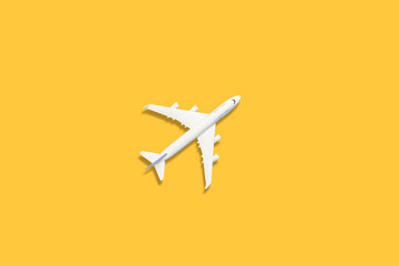 Flat lay design of travel concept with plane on yellow background with copy space.