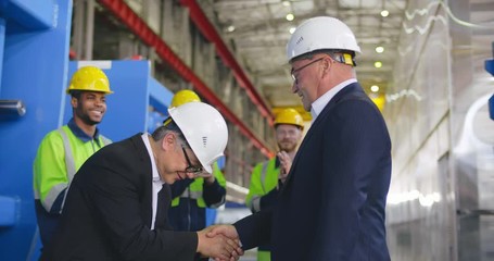 Meeting of Caucasian and Asian multi ethnic business delegations partners suppliers and handshake. Contractors shake hands in modern factory. Korean businessman bows traditionally