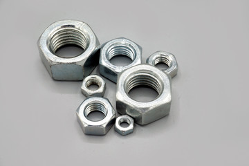 Metal nuts isolated on gray background. New and shiny chrome nuts. Copy space.